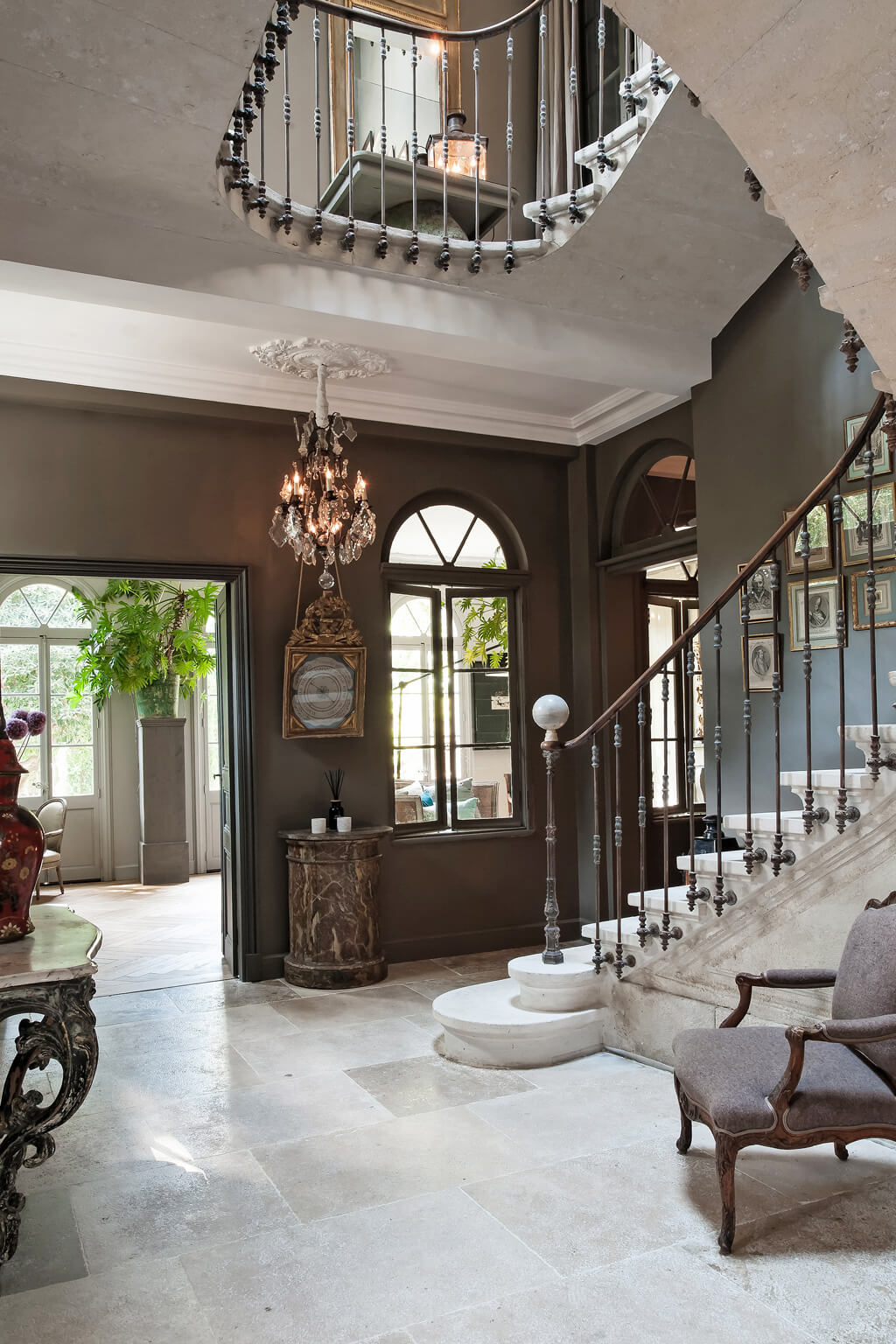 French gray walls contrast with creamy limestone in an Avignon mansion entry. Come see a Breathtaking French Château Tour in Provence With Photo Gallery of Historical Architecture, Dramatic Eclectic Interiors & Oddities!