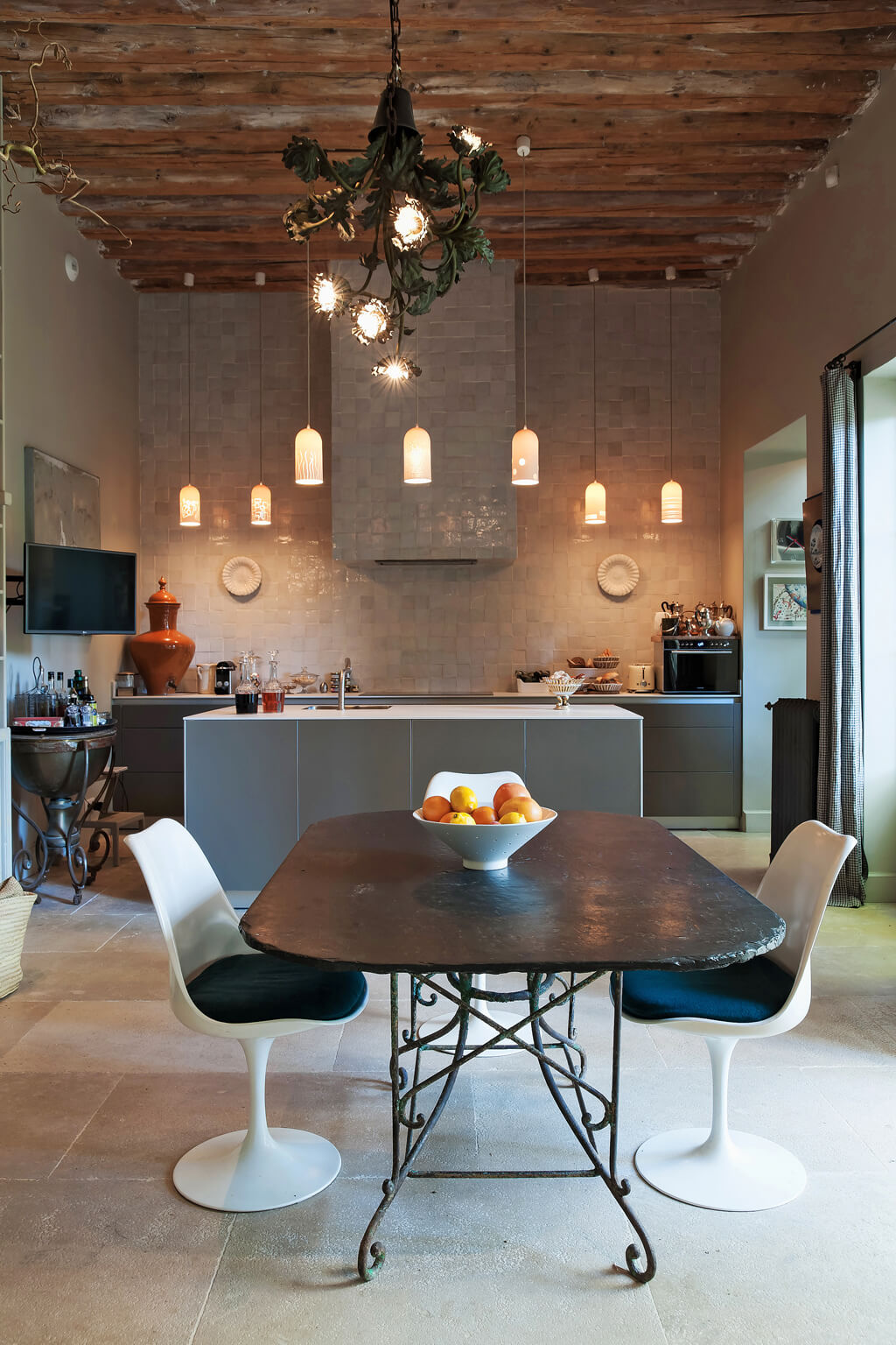 Tulip chairs in a dining area of a lounge with zellige tiles. Come see a Breathtaking French Château Tour in Provence With Photo Gallery of Historical Architecture, Dramatic Eclectic Interiors & Oddities!