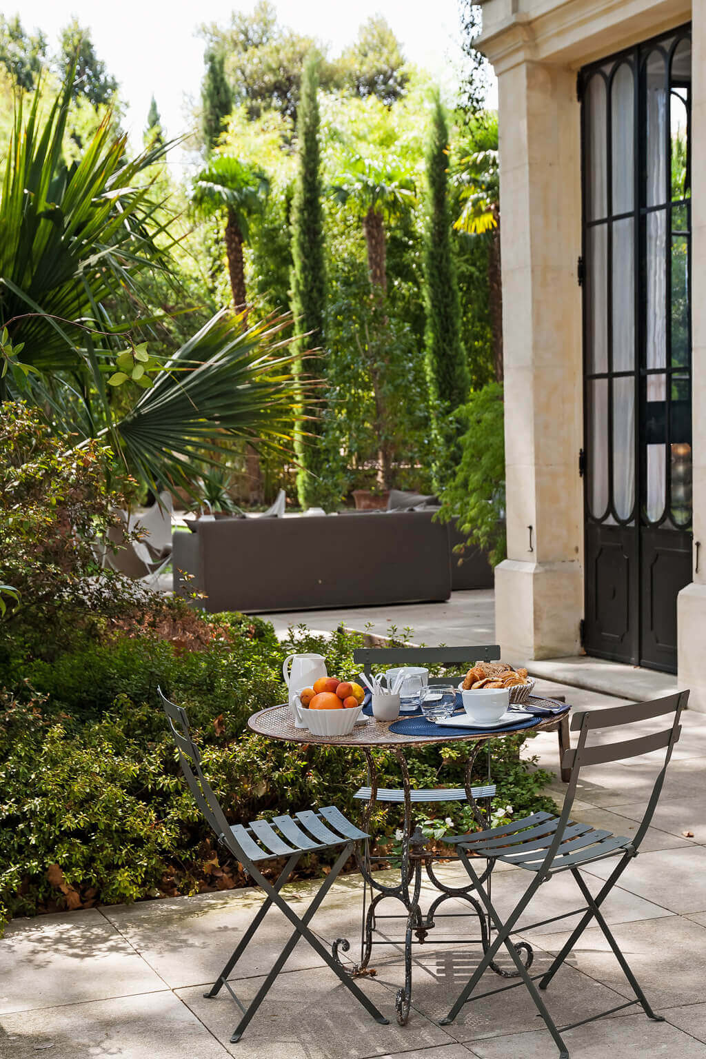 Bistro set in a peaceful Avignon garden. Come see a Breathtaking French Château Tour in Provence With Photo Gallery of Historical Architecture, Dramatic Eclectic Interiors & Oddities!