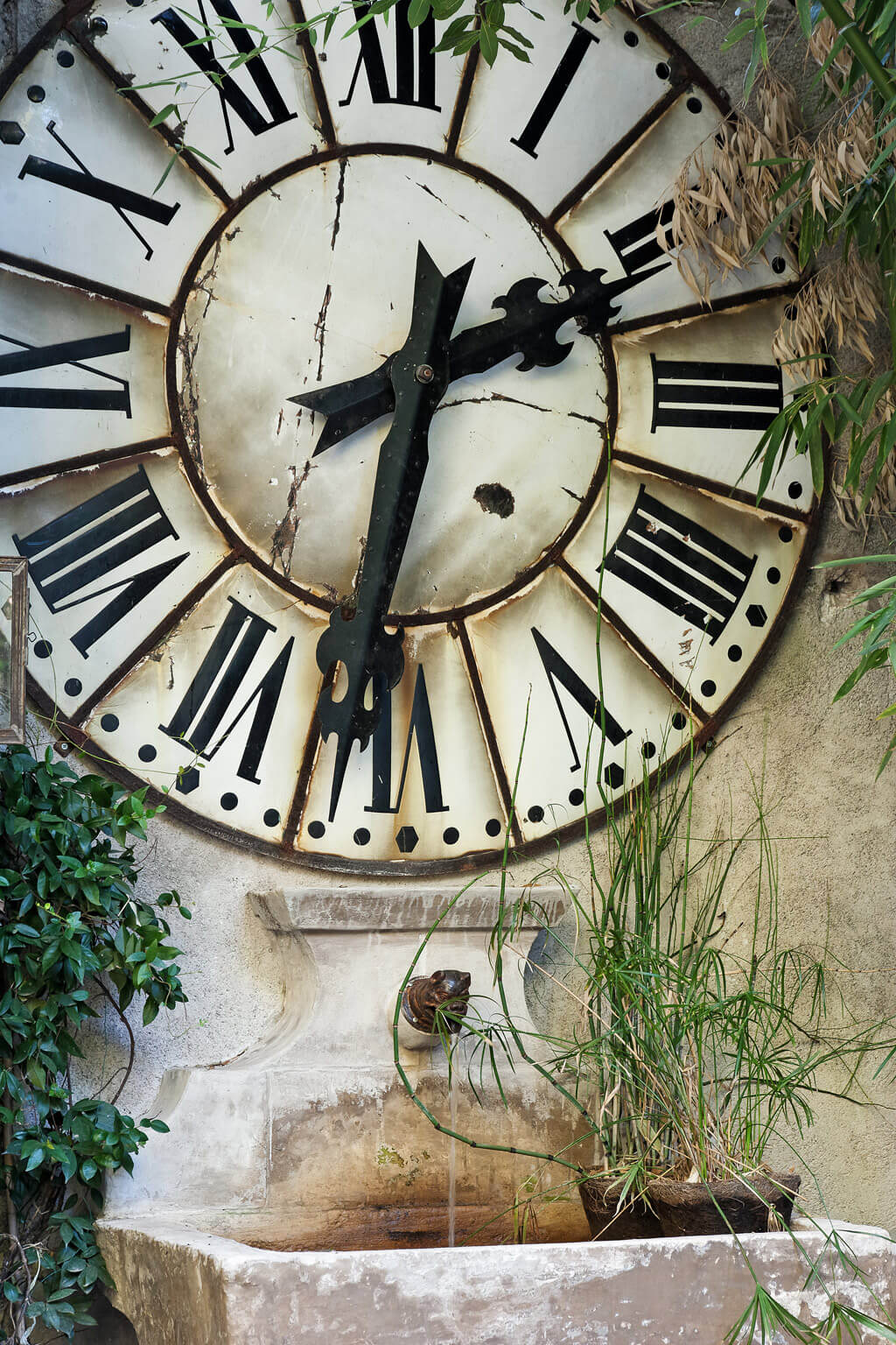 Stone fountain and huge clock with roman numerals. Beautiful French country garden inspiration from a luxurious property in the South of France. Breathtaking 19th century restored French chateau with largest private garden in Avignon. Avignon Hôtel Particulier. Photo: Haven In.