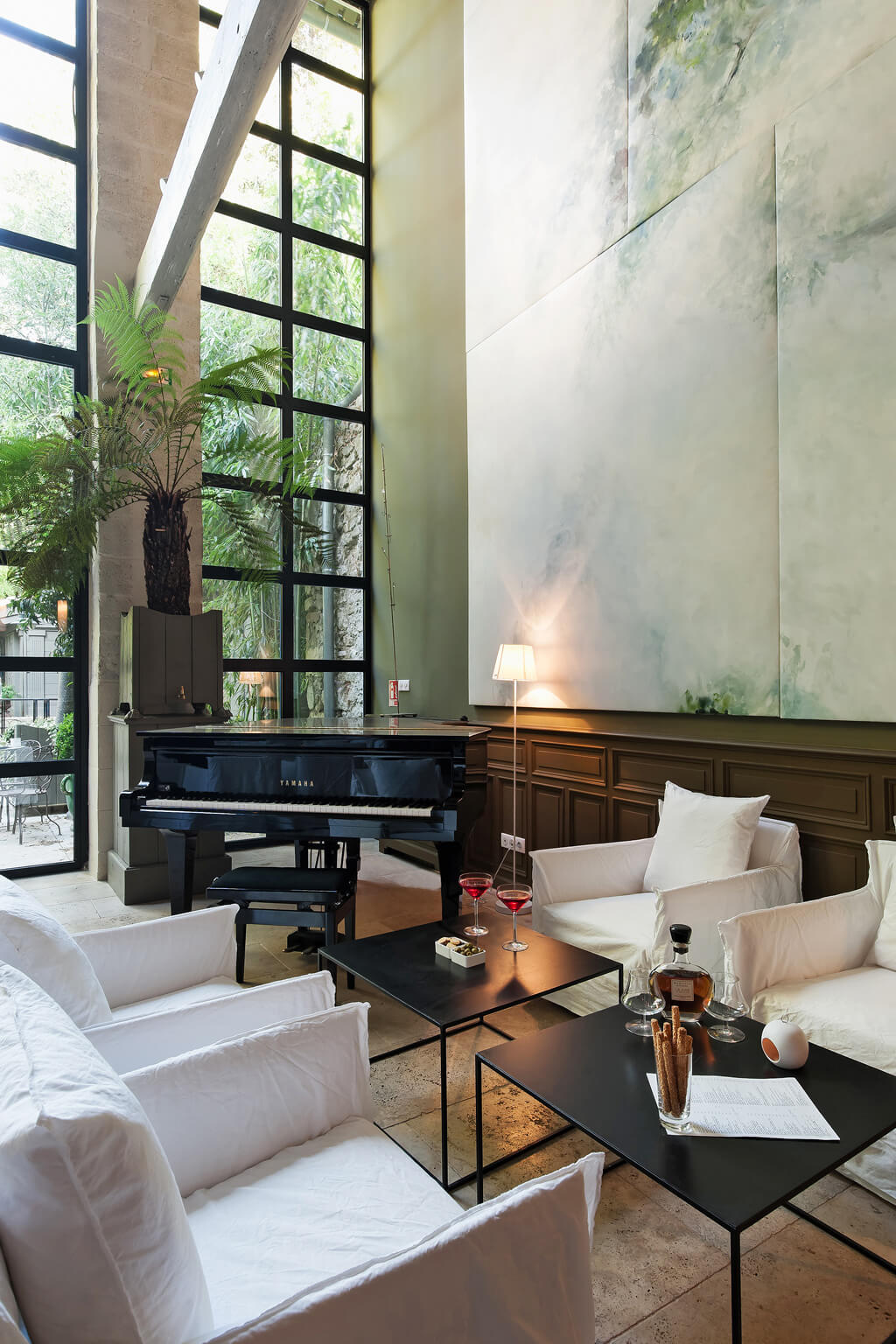 Grand piano and modern white slipcovered chairs in a restored 19th century Avignon mansion. Photo: Haven In.