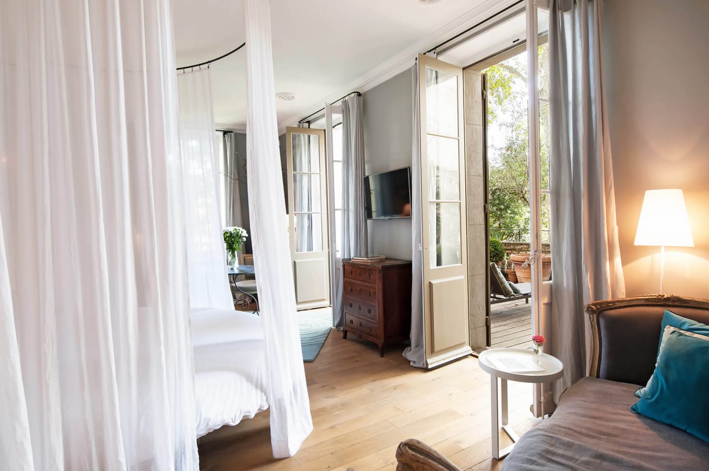 Two sets of French doors in this bedroom welcome in the outdoors. Serene French Country Style interior design inspiration. The Serenity Suite at Avignon Hôtel Particulier. Luxurious and timeless restored 19th century French chateau in the South of France. Provencal romance, traditional architecture, modern French design, unique art, and European antiques. Photo: Haven In.