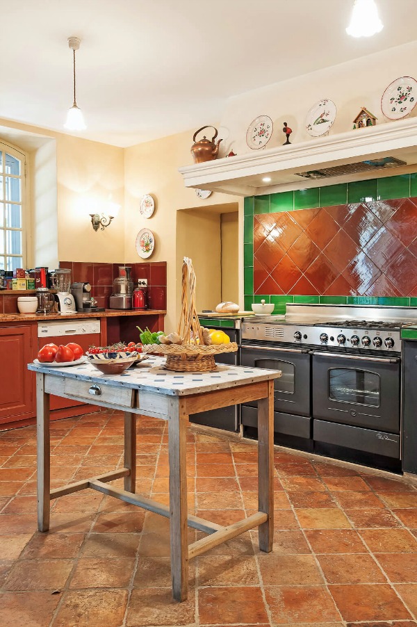 Terracotta and green pair beautifully in a traditional, Old World, hardworking kitchen with professional range in a Provence vacation villa - Haven In. #terracotta #frenchcountry #frenchkitchen