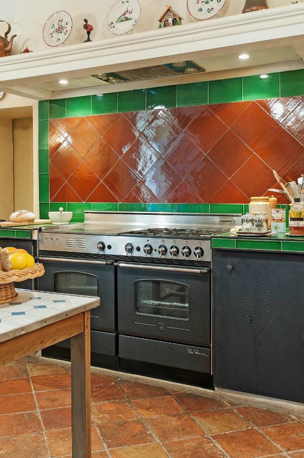 Detail of a French kitchen's backsplash with terracotta and green tiles and Old World style - Haven In.