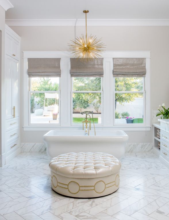 Tufted ottoman and luxurious freestanding tub in marble bathroom. Modern Chic Home in the Southwest. E&A Builders. Pinnacle Conceptions. Jaimee Rose Interiors. #modern #French #housedesign #luxuryhome