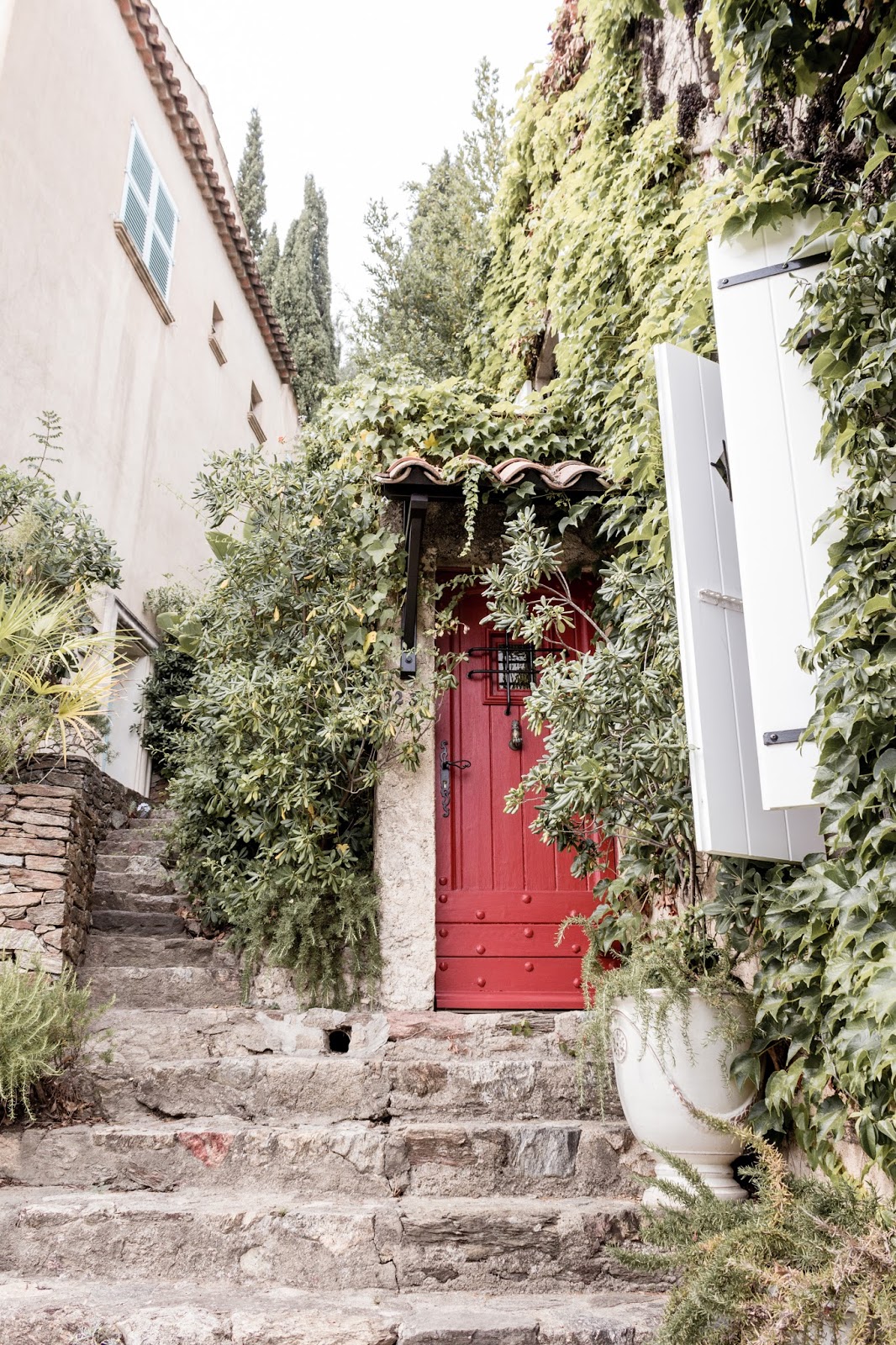 Red door and rustic French Country Provence curb appeal with climbing vines, crumbling stone, and weathered age. Photo: The Flying Dutchwoman. 