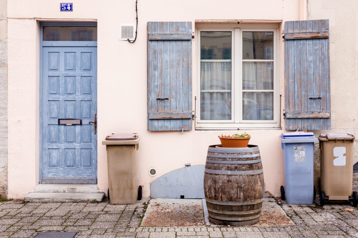 Rustic French Country Doors in Provence and gorgeous curb appeal with climbing vines, crumbling stone, and weathered age. Photo: The Flying Dutchwoman. #provence #southoffrance #exteriors #weathereddoors #rusticdoor #frenchcountryside #summerinfrance #frenchcountry #frenchfarmhouse #frontdoor #sttropez