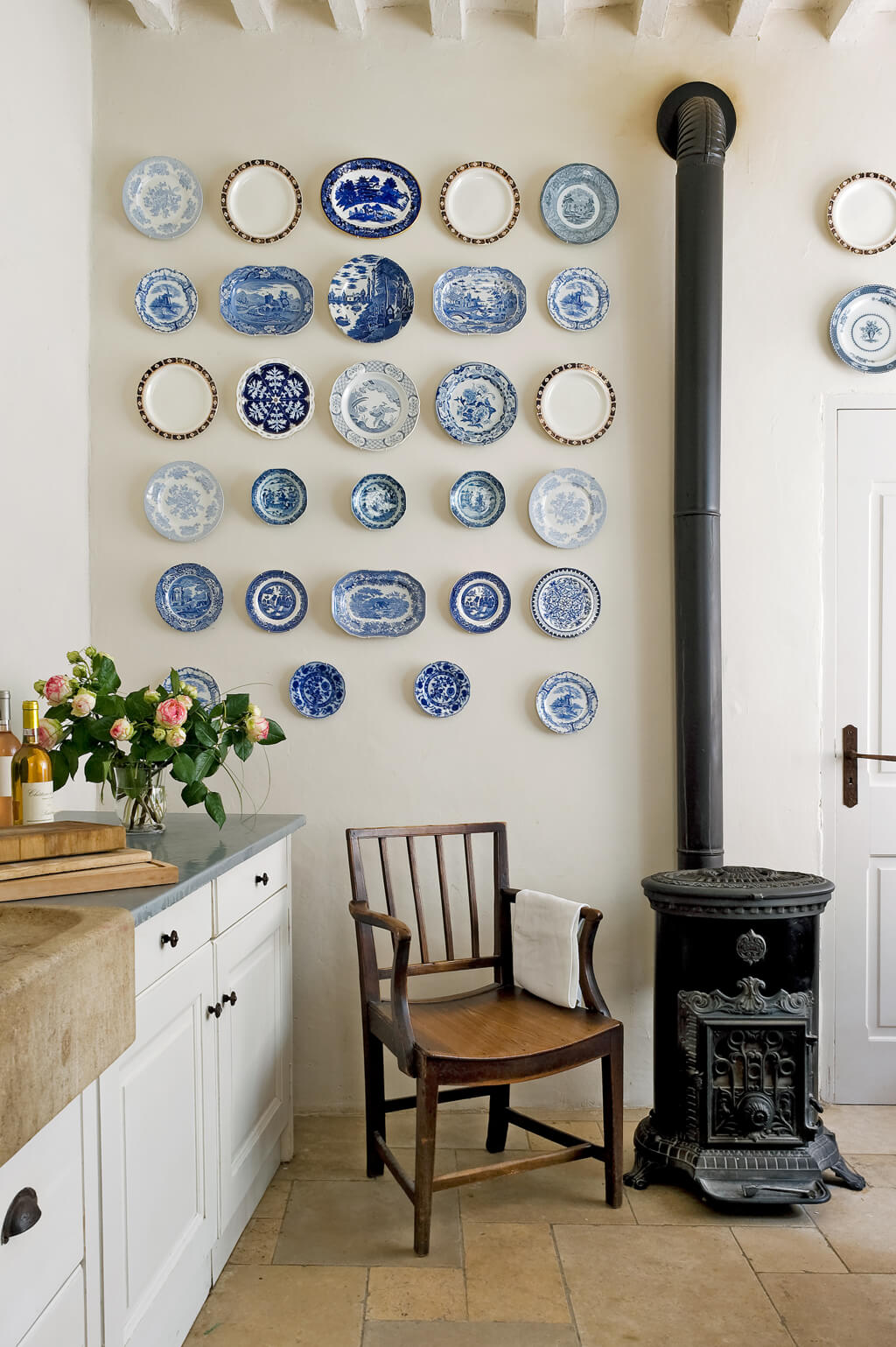 Beautiful French country kitchen in Provence with wood stove, blue plates on walls and stone sink. #frenchkitchen #provencekitchen #oldworldkitchen #frenchcountrykitchen