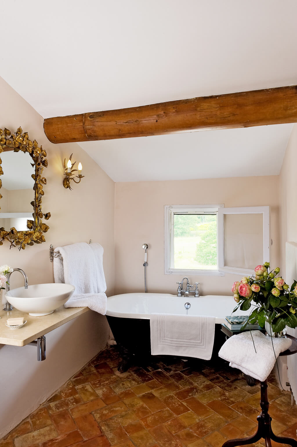 Old World French bathroom with clawfoot tub, terracotta floor, and pale plaster walls - Villa St.-Saturnin by Haven In.