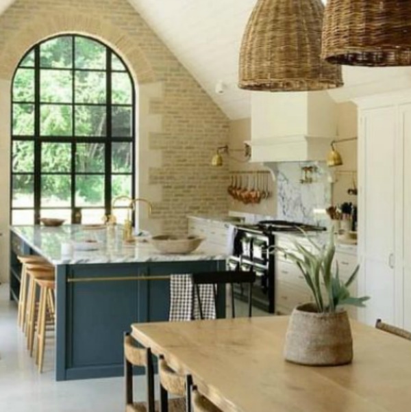 Breathtaking, elegant, and rustic luxe English country kitchen by deVOL kitchens in the UK with bespoke cabinetry, AGA stove, steel windows and doors, woven pendants, and copper accents. Interior design by Susie Atkinson.