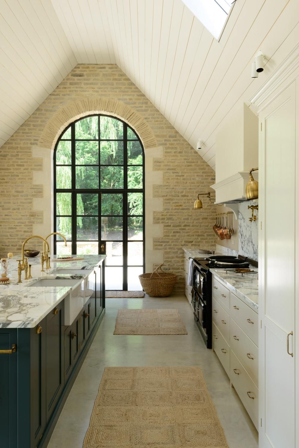 Breathtaking, elegant, and rustic luxe English country kitchen by deVOL kitchens in the UK with bespoke cabinetry, AGA stove, steel windows and doors, woven pendants, and copper accents. Interior design by Susie Atkinson.