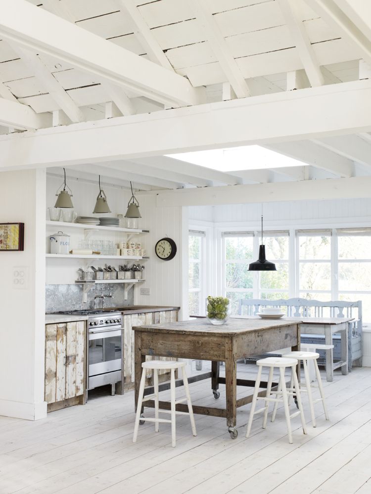 White plays a starring role in this rustic English cottage kitchen with rustic vintage farm table and industrial accents. See more interiors with calm white in this inspiring post!