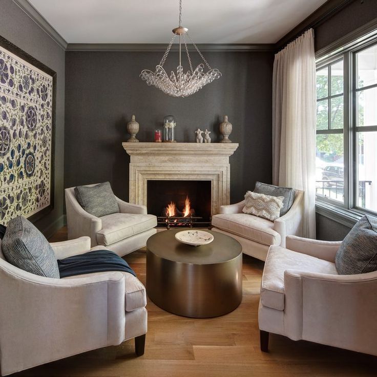 Dark grey walls and beautiful stone fireplace with chairs arranged for conversation. Cari Ginnoulias. #fireplace #cozy #interiordesign