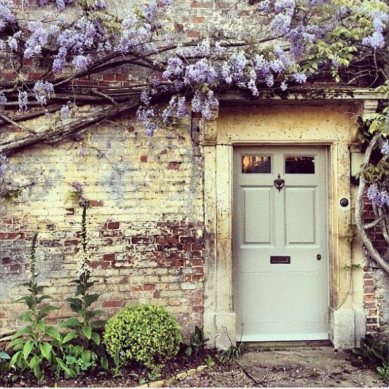 Charming English country cottage with wisteria and weathered brick for a storybook exterior! #Englishcountry #Englishcottage #wisteria #cottageexterior #stonecottage #storybook #houseexterior