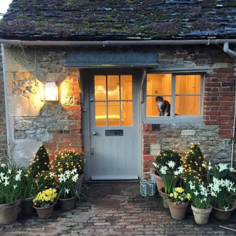 Charming English country cottage with wisteria and weathered brick for a storybook exterior! #Englishcountry #Englishcottage #wisteria #cottageexterior #stonecottage #storybook #houseexterior