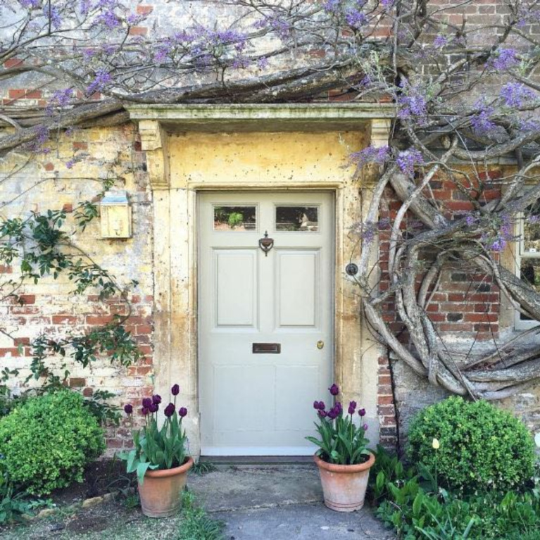 Charming English country cottage with wisteria and weathered brick for a storybook exterior! #Englishcountry #Englishcottage #wisteria #cottageexterior #stonecottage #storybook #houseexterior