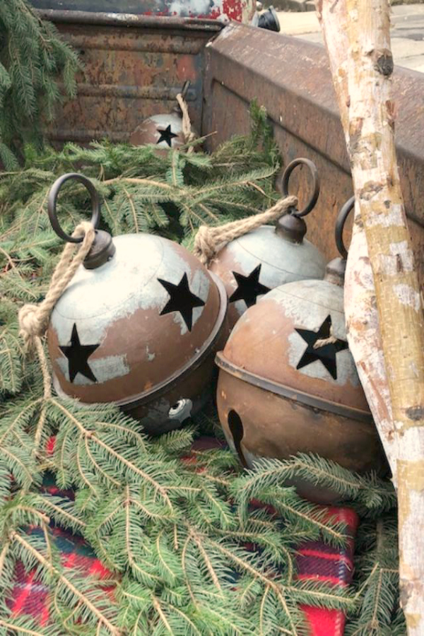 Large rusted metal Christmas bells in the back of a vintage pickup. Come discover Christmas Decorating Plaids Buffalo Checks & American Country Style! #hellolovelystudio #farmhousechristmas #christmasdecor #plaid #buffalochecks #countrychristmas