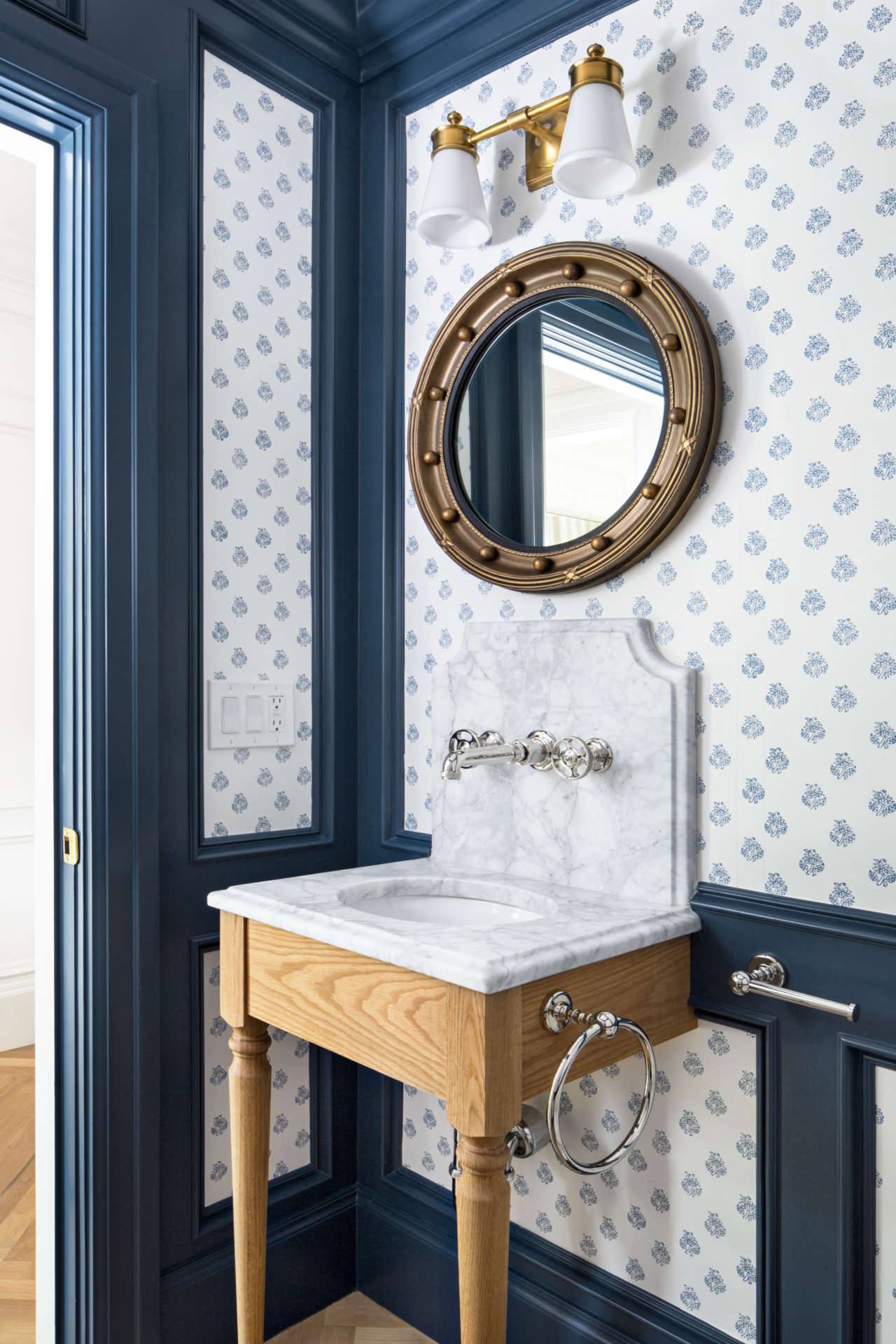 Traditional powder room with wood console sink with marble top,  blue and white wallpaper and navy blue trim. The Fox Group. Come explore these timeless design ideas...hello lovely indeed.#powderroom #traditional #thefoxgroup