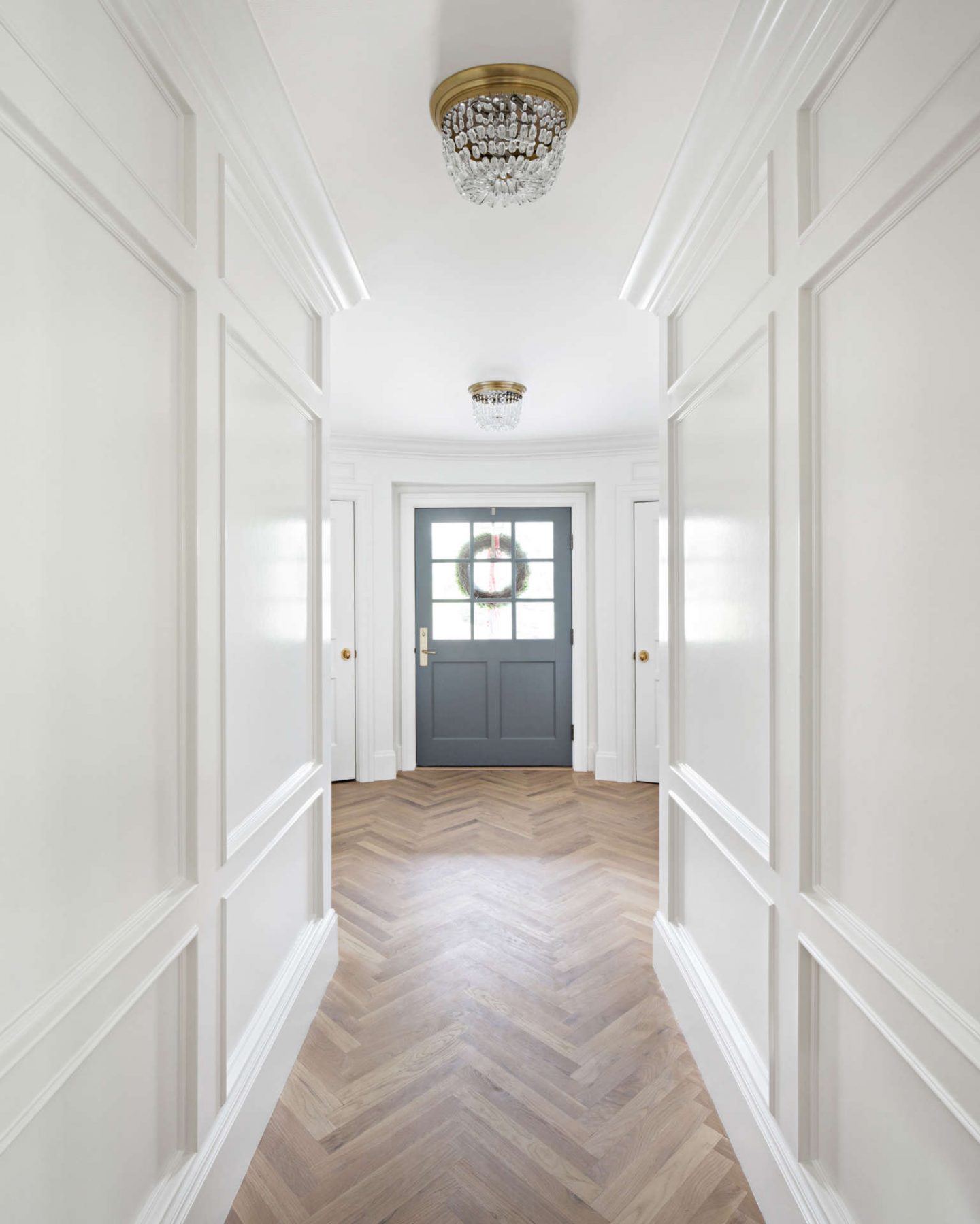 Herringbone flooring and beautiful paneled walls painted Benjamin Moore Simply White. The Fox Group.  Come see: Best White Paint Colors: 6 Favorites Designers Turn To in case you need paint color ideas. #benjaminmooresimplywhite #interiordesign #thefoxgroup