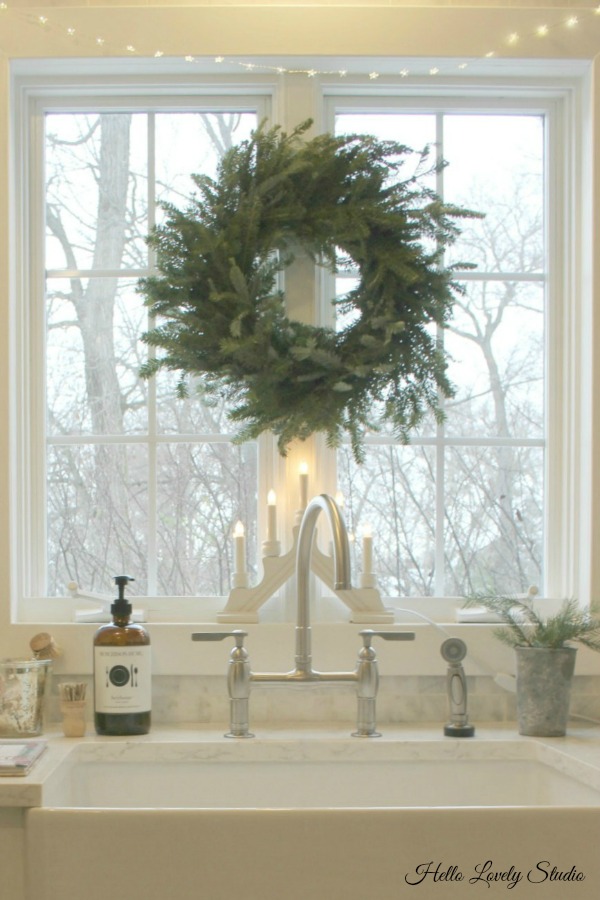 White Christmas decor inspiration from a simple kitchen sink with fresh wreath. Hello Lovely Studio.