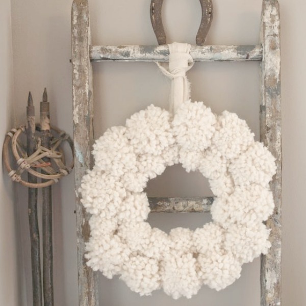 My pom pom wreath on a chippy ladder with vintage european ski poles and horseshoe. #hellolovelystudio