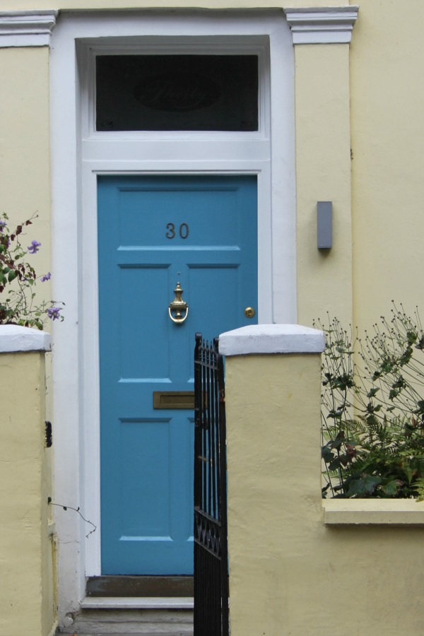 French blue painted front door of a yellow row house. Hello Lovely Studio. Come tour these gorgeous front doors in Notting Hill and Holland Park...certainly lovely indeed. Curb appeal and Paint Color Inspiration. Lovely London Doors & Paint Color Ideas!