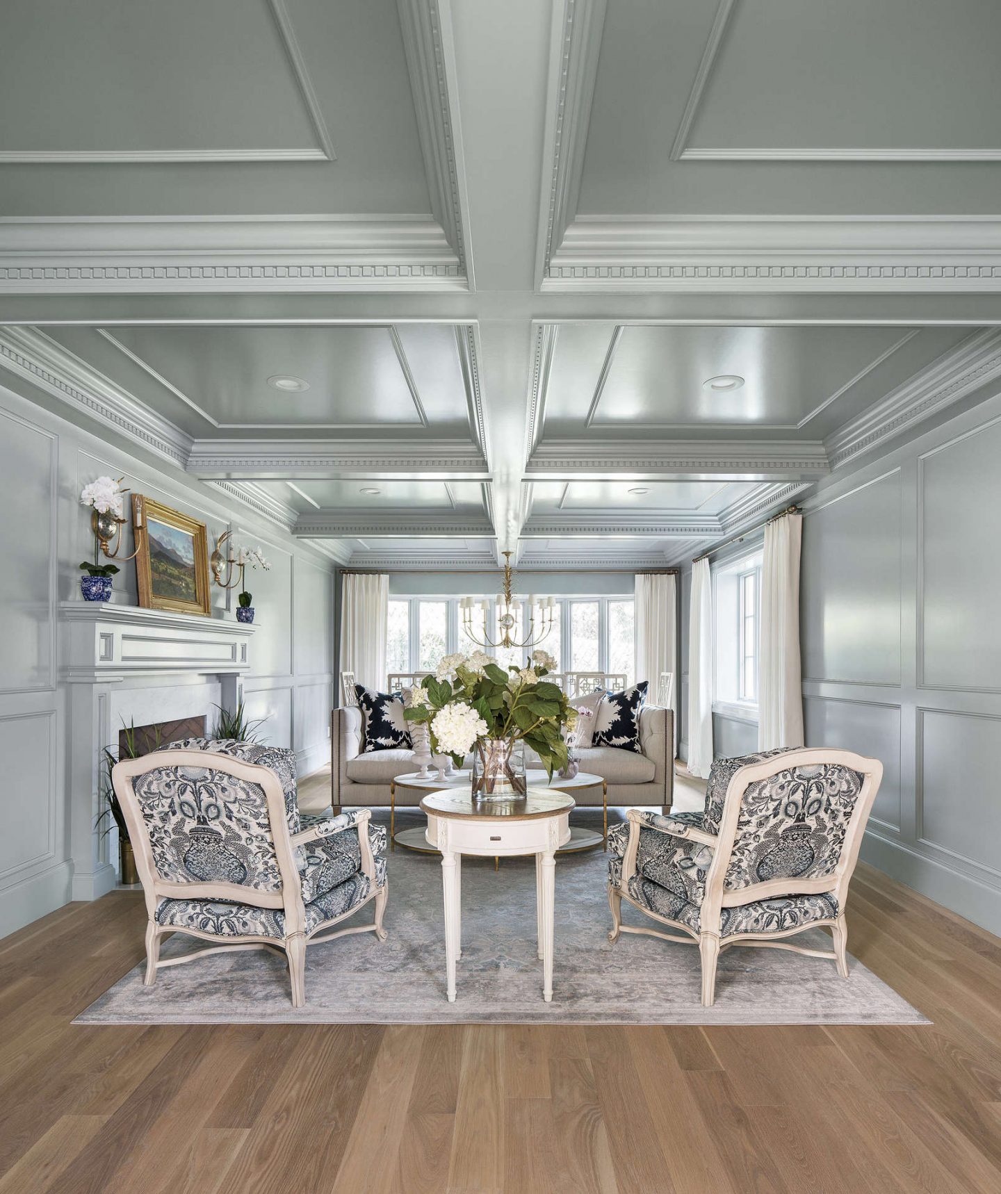 Serene and ethereal aqua blue gray painted paneled walls and coffered ceiling in traditional living room in a Tudor home. More timeless decorating ideas ahead! #thefoxgroup #livingroom #interiordesign