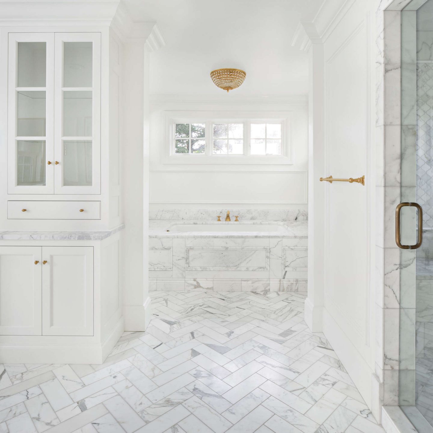 Calacatta marble tile and tub surround in a luxurious white classic bathroom. Come explore these timeless design ideas...hello lovely indeed.  #thefoxgroup #bathroomdesign #calacattamarble 