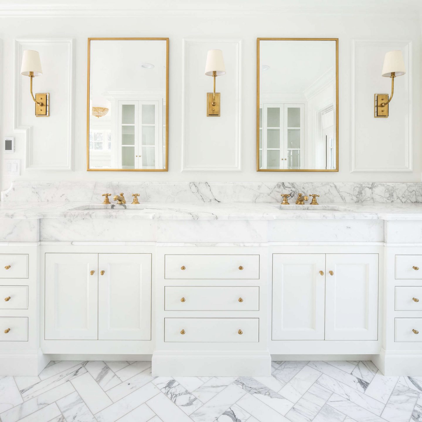 Hulton sconces (Thomas O'Brien for VC) in a luxurious white marble bath with bespoke vanities and antique brass hardware. #thefoxgroup #visualcomfortlighting #calacattamarble