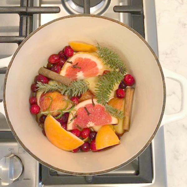 Pot of colorful fruit, greenery, and herbs simmering for a holiday scented home - Hello Lovely Studio. #potpourri #christmas #scents #simmers