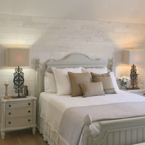 My serene white French country bedroom with Stikwood accent wall, cottage style wood furniture, Paris gate lamps (RH) and white oak flooring - Hello Lovely Studio. Come see photos of gorgeous white country interiors!