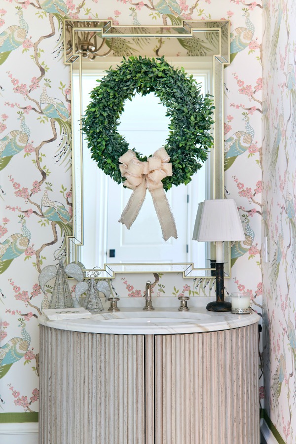 Beautiful fresh green Christmas wreath with ivory bow hung on a mirror in a powder room in an Atlanta showhouse. Beautiful holiday decor inspiration from interior designers and bloggers. Come discover 28 Amazing Christmas Decorating Ideas! #christmasdecor #holidaydecorating