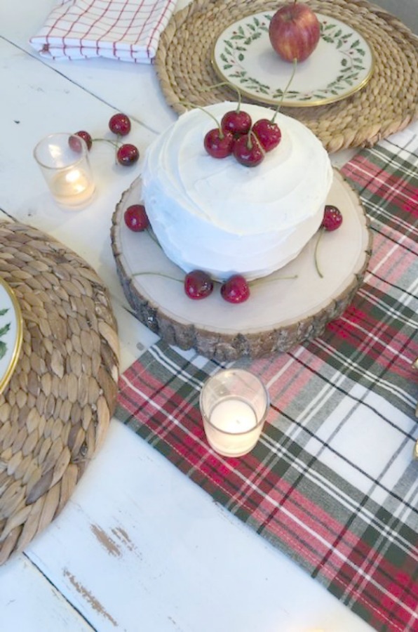 Farmhouse Christmas tablescape with red cherries, plaid, and holly Lenox plates. Hello Lovely Studio. Come find the mini cake recipe and sources for decor! #hellolovelystudio #tablescape #christmas #cherries #cake
