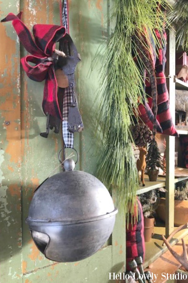 Oversized galvanized Christmas bell suspended from green vintage door at Trove Vintage. #holidaydecor #christmasdecorating #bell #vintagestyle