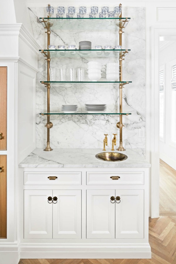 The Fox Group designed elegant white marble kitchen with unlacquered brass and glass shelves. #timelesskitchens #bespokekitchendesign