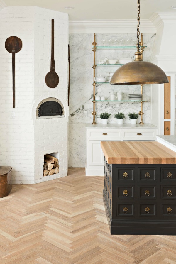 Beautiful kitchen design with herringbone wood floor, butcher block top work table and white brick. Design by the Fox Group.