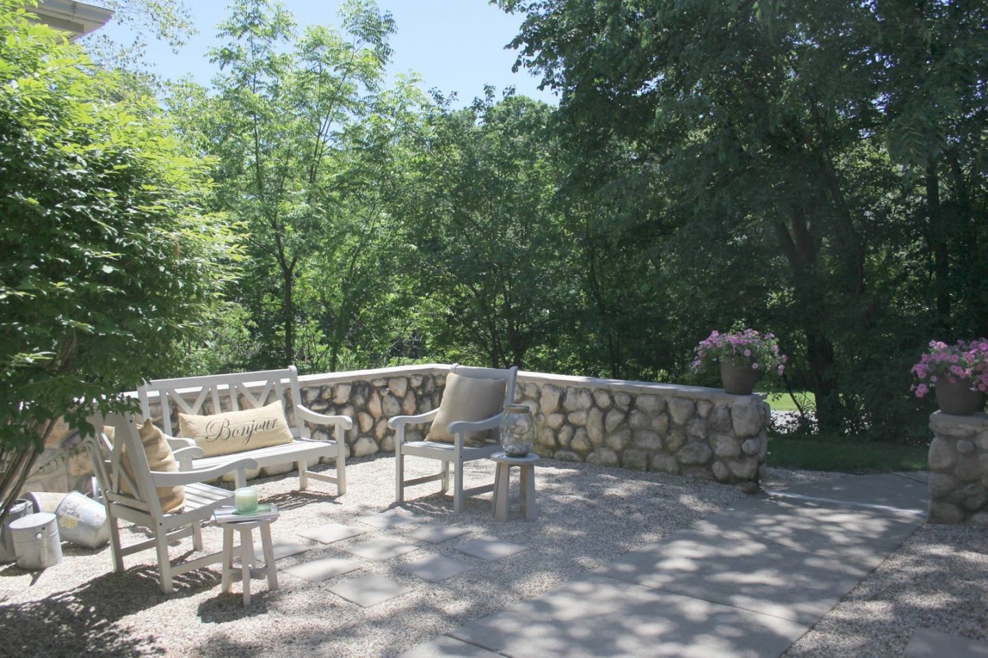 French country courtyard with stone walls, pea gravel, boxwood, lavender, wood furniture, and vintage touches. Come see the before and after of our project on Hello Lovely Studio. #hellolovelystudio #frenchcountry #courtyard #gardeninspiration #renovation 