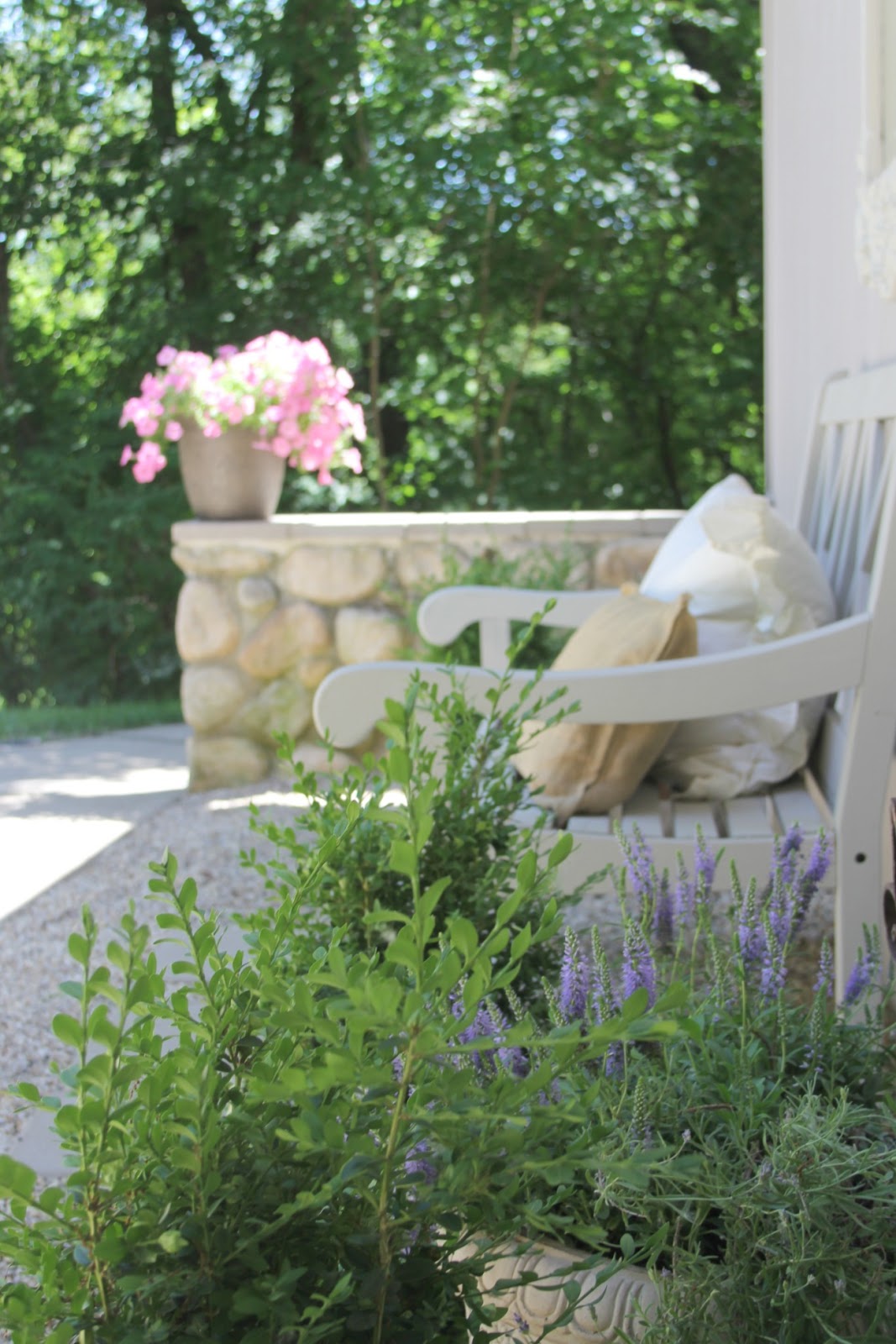 French country courtyard with stone walls, pea gravel, boxwood, lavender, wood furniture, and vintage touches. Come see the before and after of our project on Hello Lovely Studio. #hellolovelystudio #frenchcountry #courtyard #gardeninspiration #renovation