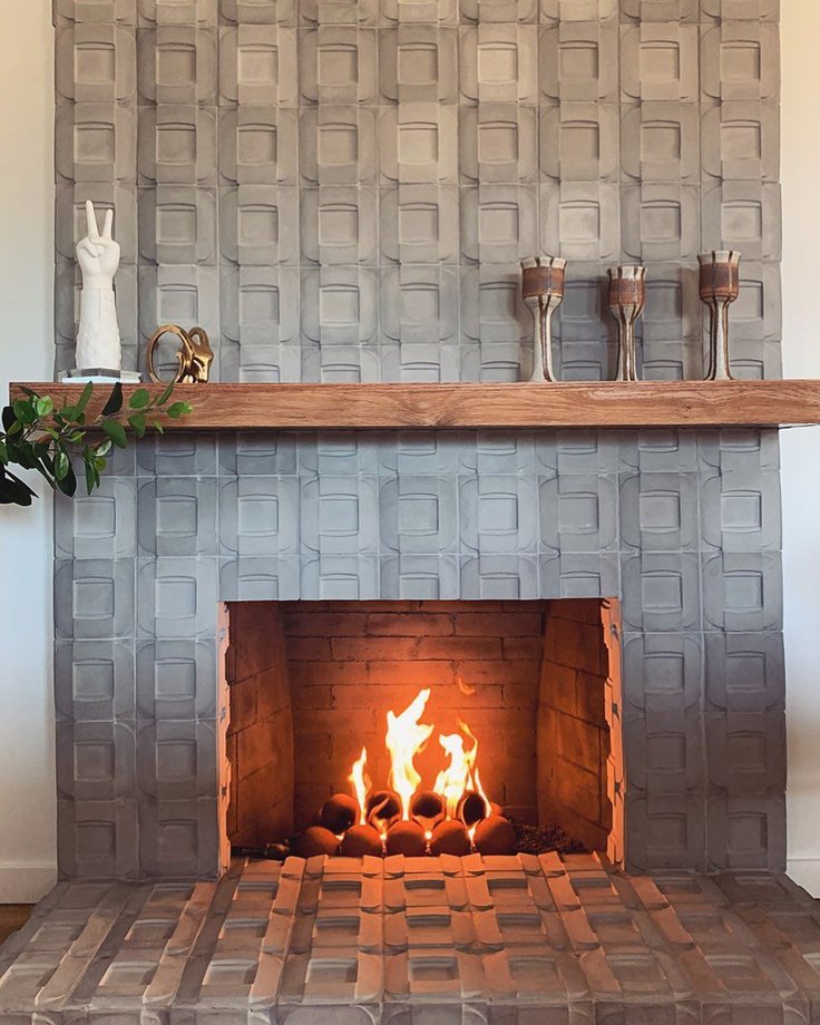 Edgy, dramatic, and organic, this cement tiled fireplace (@renoveau_hom) has geometric chic and rustic elegance. #cementtile #fireplace #interiordesign