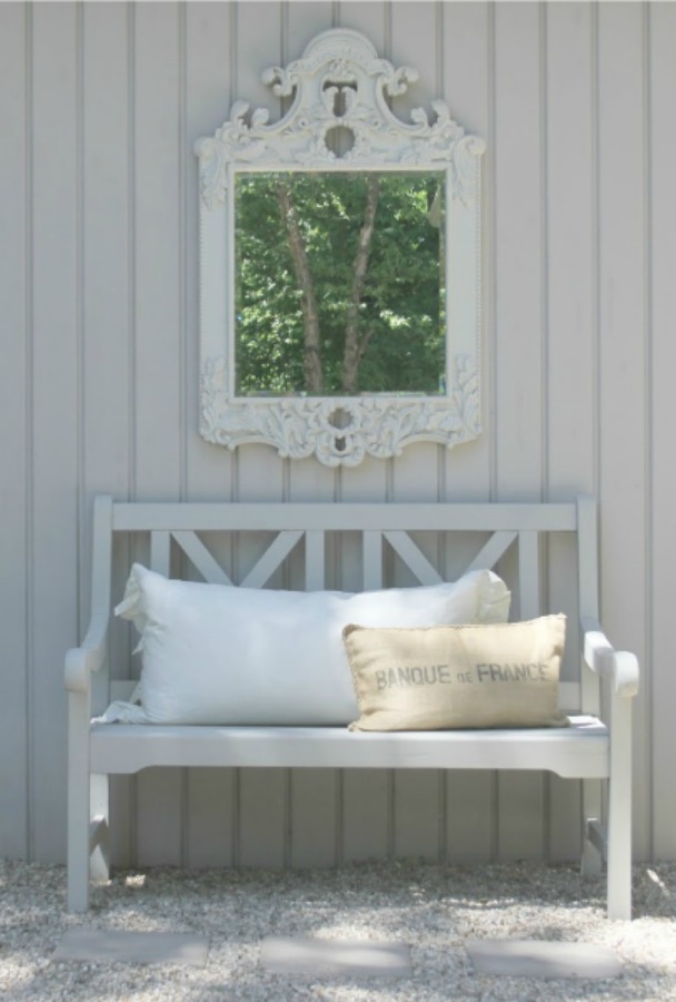 French country courtyard with stone walls, pea gravel, boxwood, lavender, wood furniture, and vintage touches. Come see the before and after of our project on Hello Lovely Studio. #hellolovelystudio #frenchcountry #courtyard #gardeninspiration #renovation 