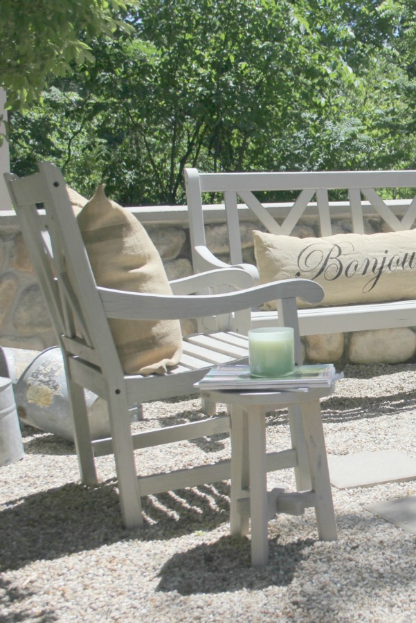 French country courtyard with stone walls, pea gravel, boxwood, lavender, wood furniture, and vintage touches. Come see the before and after of our project on Hello Lovely Studio. #hellolovelystudio #frenchcountry #courtyard #gardeninspiration #renovation