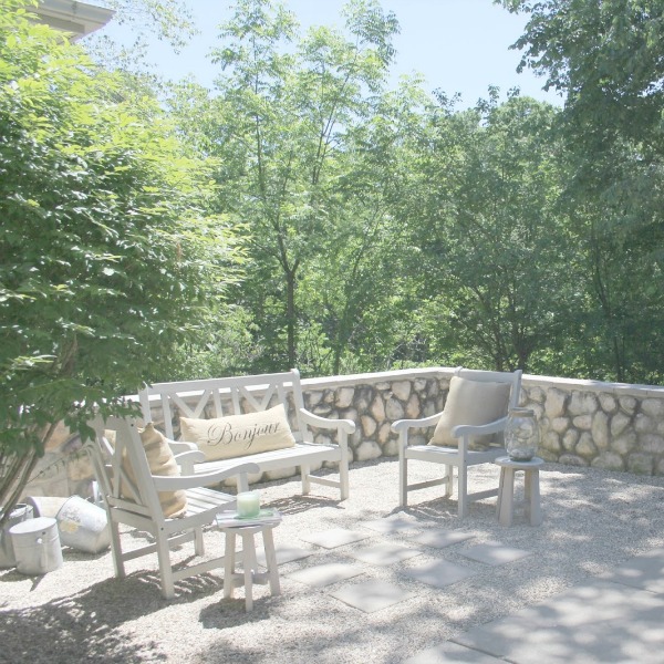 French country courtyard with stone walls, pea gravel, boxwood, lavender, wood furniture, and vintage touches. Come see the before and after of our project on Hello Lovely Studio. #hellolovelystudio #frenchcountry #courtyard #gardeninspiration #renovation 