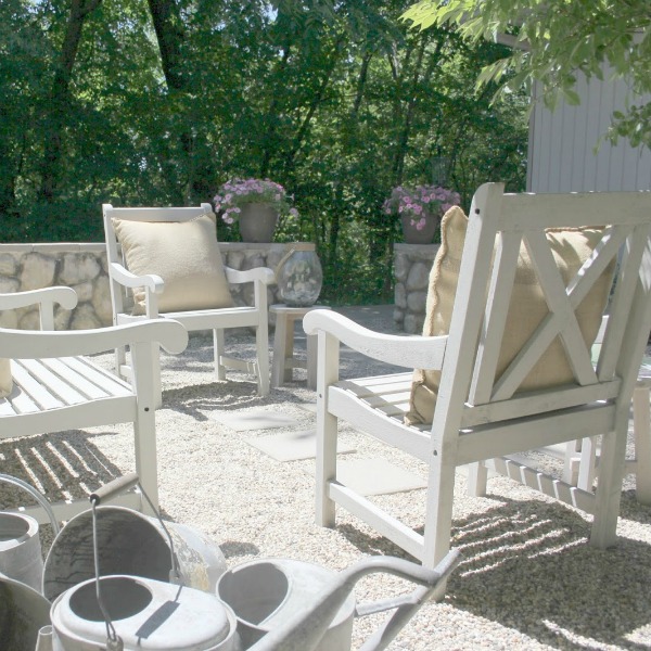 French country courtyard with stone walls, pea gravel, boxwood, lavender, wood furniture, and vintage touches. Come see the before and after of our project on Hello Lovely Studio. #hellolovelystudio #frenchcountry #courtyard #gardeninspiration #renovation 