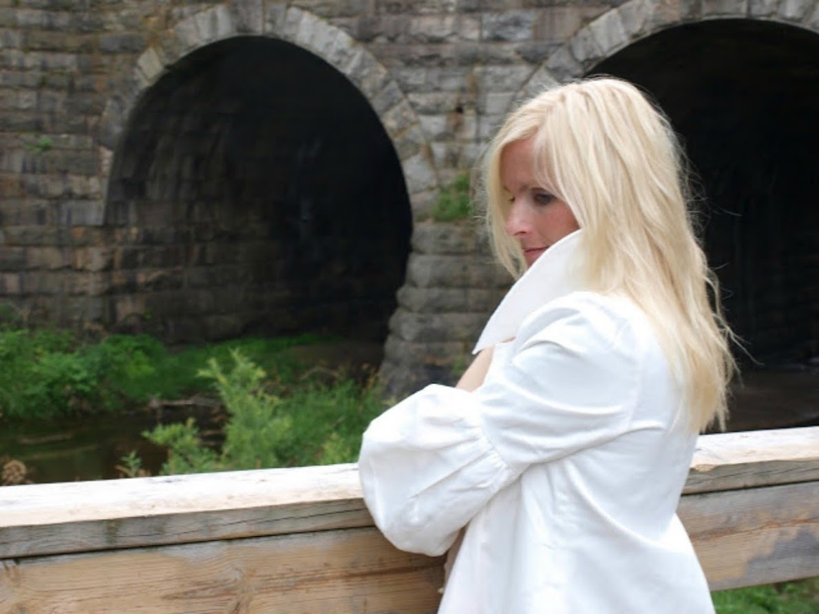 Michele of Hello Lovely Studio at historic stone bridge in white jacket with balloon sleeves. #hellolovelystudio