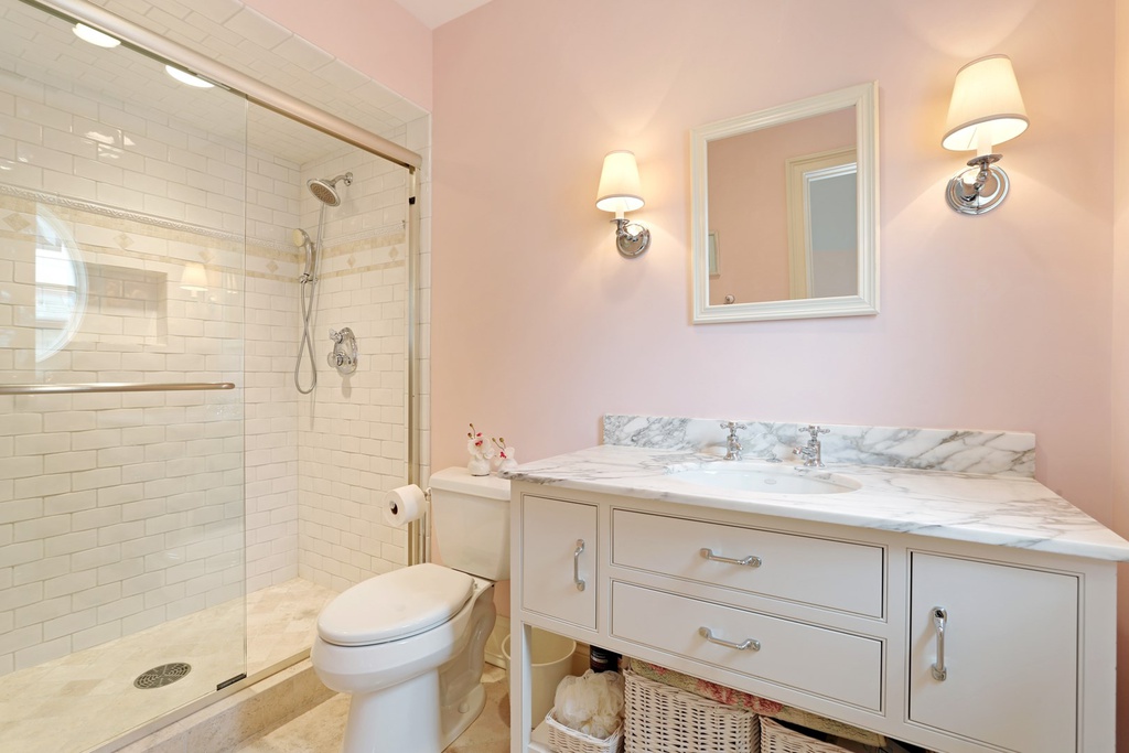 Beautiful pink walls in a classic and luxurious white bathroom in a Hinsdale manse. Come explore more Country French Decor Ideas from luxurious and grand homes.