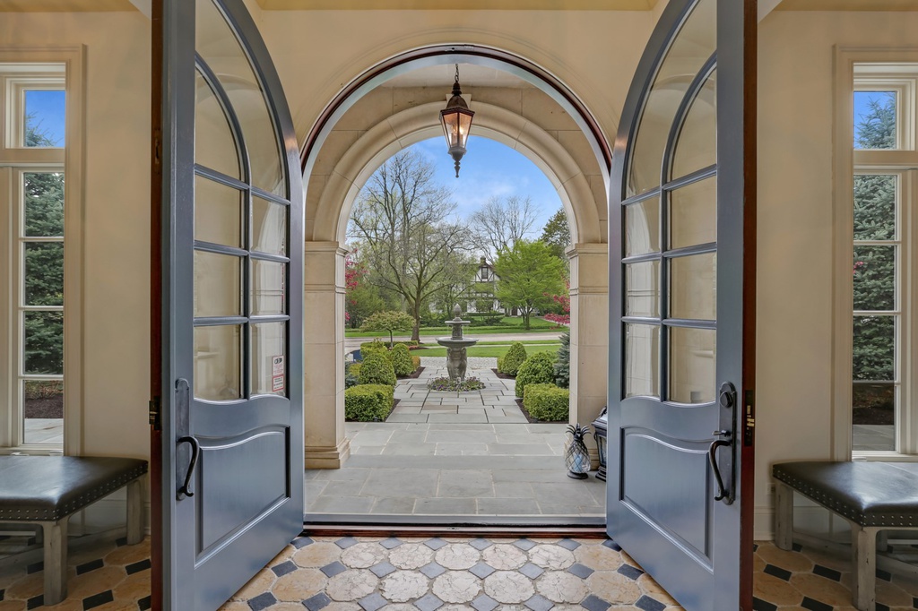 Grand double French arched doors at the entrance to a magnificent Hinsdale manse. Come explore more Country French Decor Ideas from luxurious and grand homes.