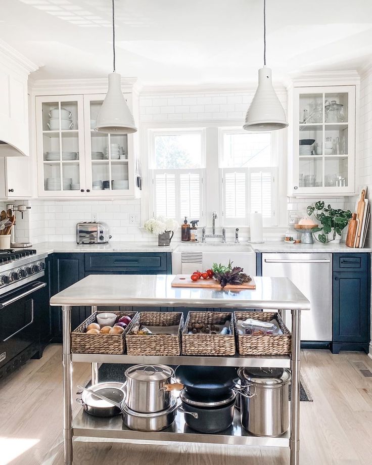 Stainless work table in industrial farmhouse kitchen with white pendants and two tone cabinets - Most Lovely Things. #stainlessworktable #industrialfarmhouse #farmhousekitchen