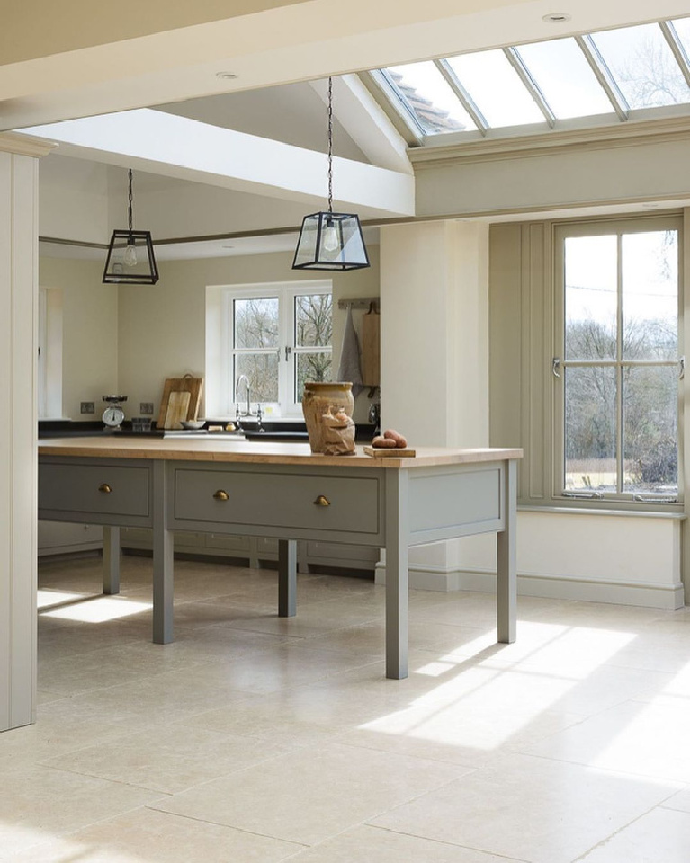 Exquisite and ethereal European country kitchen in an orangery with limestone tile floor and skylights featuring bespoke designs by deVOL.