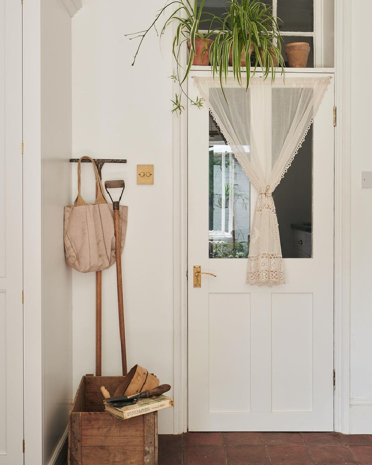 Serene white English country kitchen moment featuring a brass dimmer switch outside a porch door with window - deVOL kitchens.