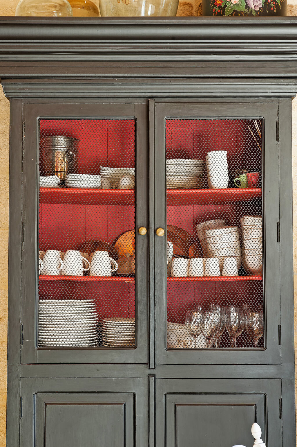 Charcoal grey French farmhouse cupboard with wire door inserts and red interior.